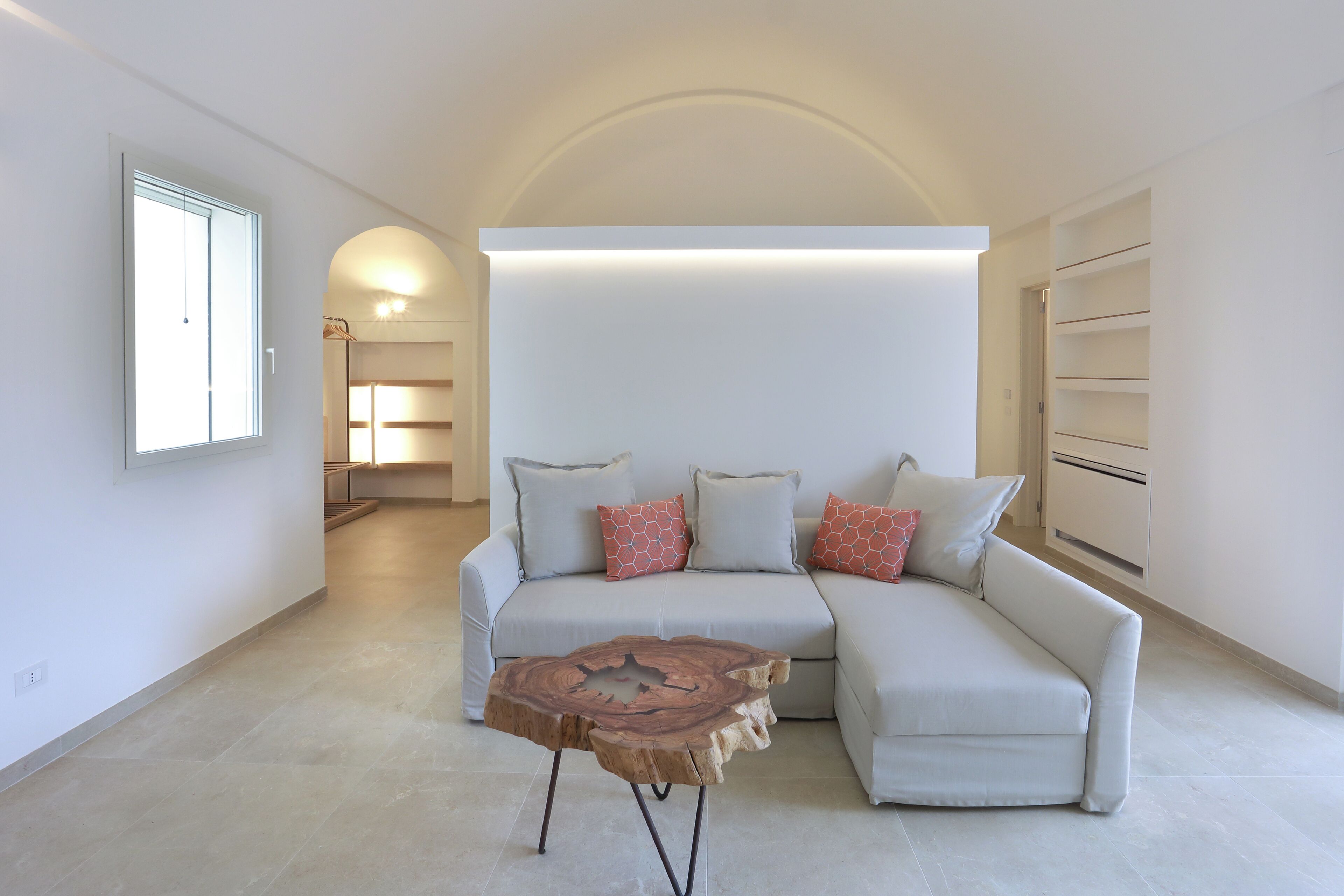 A modern living room with a light-colored sofa, a wooden coffee table, and a large window.