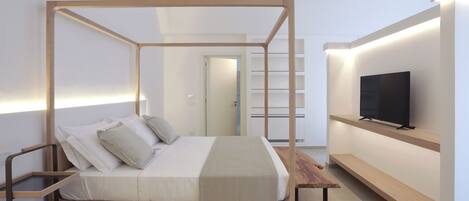 A modern bedroom with a four-poster bed, a television on a shelf, and a minimalist design.
