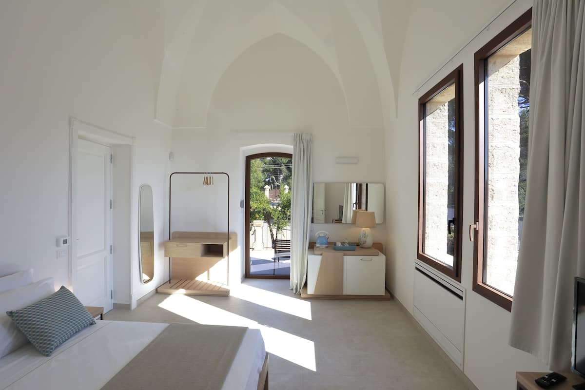 A modern bedroom with a bed, bedside table, and a view of the outside.