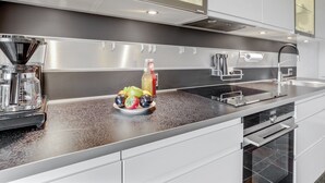 Een moderne keuken met een roestvrijstalen spoelbak, een inbouwoven en een raam met glas boven het aanrecht.