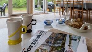 Une table avec un journal, une assiette de pain et deux tasses.