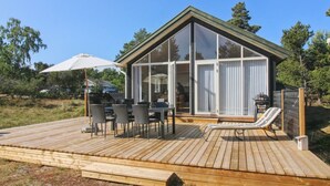 Une maison moderne dotée d’une terrasse, de grandes baies vitrées et de mobilier d’extérieur.
