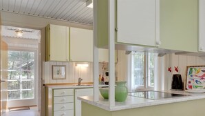 A kitchen with white cabinets, a green accent wall, and a window overlooking a garden. - "Aave" - 800m from the sea by Interhome (Aakirkeby)