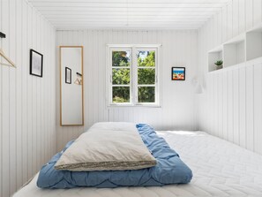 Una camera da letto con un letto, una finestra, uno specchio e una mensola a parete.
