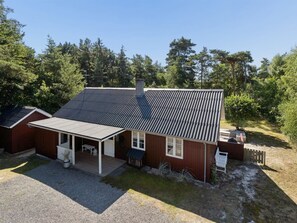 A single-story building with a sloped roof, a covered porch, and a small outdoor seating area.