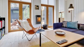 A modern living room with a fireplace, a sofa, a chair, and a coffee table. - "Nuka" - 800m from the sea by Interhome (Aakirkeby)