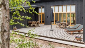 A modern wooden house with a deck, outdoor seating, and large glass doors. - "Nuka" - 800m from the sea by Interhome (Aakirkeby)