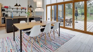 A modern kitchen with a wooden island, white chairs, and a dining table. - "Nuka" - 800m from the sea by Interhome (Aakirkeby)
