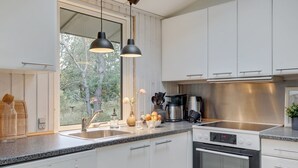 A modern kitchen with white cabinets, a stainless steel range hood, a built-in oven, a granite countertop, and pendant lighting. - "Essi" - 300m from the sea by Interhome (Aakirkeby)