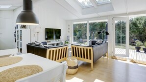A spacious living area with a high ceiling, skylights, a dining table, and a sofa. - "Essi" - 300m from the sea by Interhome (Aakirkeby)