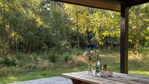 A wooden picnic table with a cushion, a bottle of liquor, and a vase with flowers. - "Chenoa" - 200m from the sea by Interhome (Aakirkeby)
