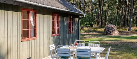 Eine Holzhütte mit einer Veranda, roten Fensterrahmen und einer Satellitenschüssel.