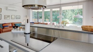 A modern kitchen with a central island, large windows, and a cozy seating area.