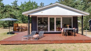 A modern house with a covered patio, outdoor seating, and a deck.