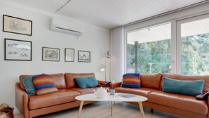 A modern living room with a brown leather sofa, a white coffee table, and framed artwork on the wall.