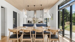 Una cocina moderna con una isla central, luces colgantes y vistas al exterior.