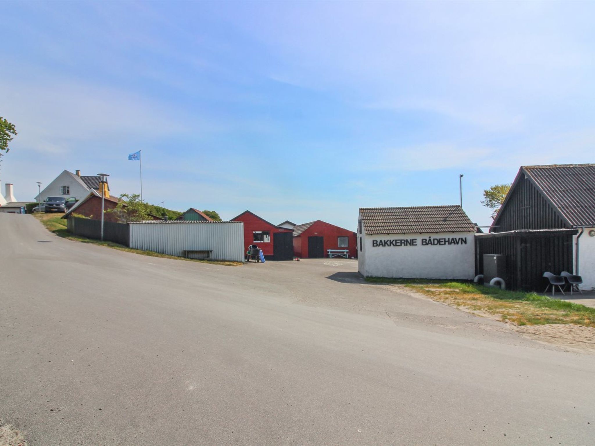 A road leading to a building with a sign reading 'BAKKERNE BADEHAVN'.