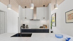 Una cocina moderna con una isla central, luces colgantes y un diseño minimalista.