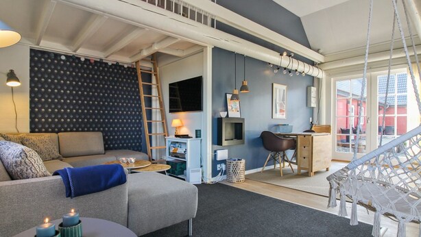A modern living room with a grey sofa, a small round table with candles, a desk with a chair, and a hanging hammock. - "Gisella" - 6km from the sea by Interhome (Aakirkeby)