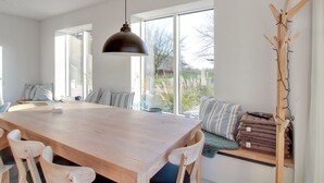 Un comedor amplio con una gran mesa de madera, sillas blancas y una lámpara colgante moderna.