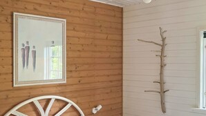 Une chambre avec une tête de lit en bois, un lit avec des oreillers rouges, un miroir fixé au mur et une décoration en forme de branche.