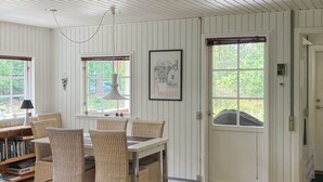 Une pièce comprenant une table à manger et des chaises, une bibliothèque et une porte avec une fenêtre.