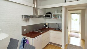 Une cuisine compacte équipée d’une cuisinière, d’un four à micro-ondes et d’un évier intégrés. Un petit coin repas avec une table et des chaises est également disponible.