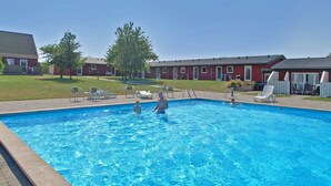 Une piscine avec des chaises longues et un bâtiment en arrière-plan.