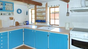 Una cocina con armarios azules, una estufa blanca y un ventanal con vistas.