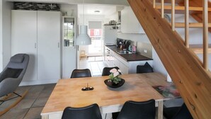 A modern kitchen with a wooden staircase, a dining area with a table and chairs, and a view of the outside. - "Karoline" - 6km from the sea by Interhome (Aakirkeby)