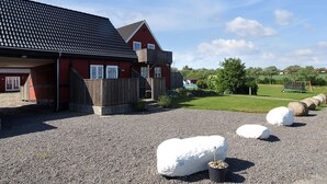 A red building with a dark roof, a wooden fence, and a gravel driveway. - "Karoline" - 6km from the sea by Interhome (Aakirkeby)