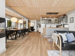Et moderne køkken med en central ø, trægulv og et spiseområde med et bord og stole.