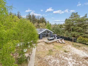 Et hus med terrasse, havemøbler og en indhegnet have.