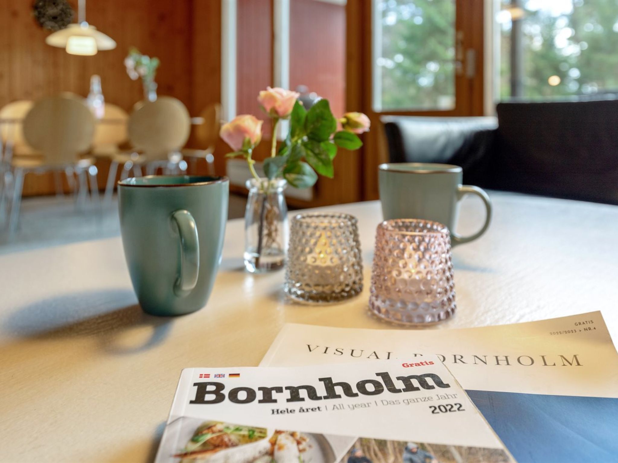 Une table avec un magazine, une tasse, un vase de fleurs, et des salières et poivrières.