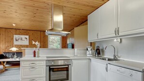 A modern kitchen with white cabinets, stainless steel appliances, and a wooden ceiling.