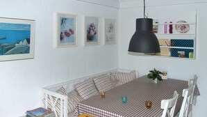 A dining area with a checkered tablecloth, white chairs, and a hanging black pendant light. - "Thorke" - 5km from the sea by Interhome (Aakirkeby)
