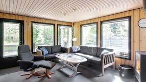 Ein modernes Blockhaus-Interieur mit einer Eckcouch, einem runden Tisch und einem Kamin.