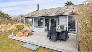 A modern house with a covered patio, outdoor seating, and a large window overlooking the landscape. - "Bondi" - 150m from the sea by Interhome (Aakirkeby)