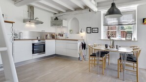 A modern kitchen with white cabinets, a built-in oven, and a dining area with a wooden table and chairs. - "Antine" - 6km from the sea by Interhome (Aakirkeby)