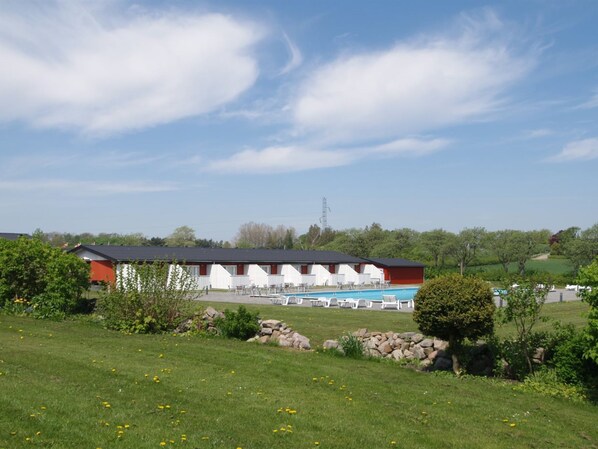 Un hotel con varias habitaciones, piscina y césped bien cuidado.