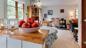 Une cuisine chaleureuse avec un îlot central en bois, un panier de pommes et un poêle rustique.