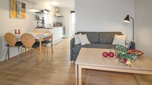 A modern living room with a grey sofa, wooden coffee table, and a dining area with a white table and chairs. - "Lutz" - 6km from the sea by Interhome (Aakirkeby)