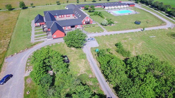 A large building with multiple red-roofed structures, a swimming pool, and surrounding green fields. - "Lutz" - 6km from the sea by Interhome (Aakirkeby)