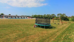 Ein Rasenbereich im Freien mit Trampolin und Schaukel.