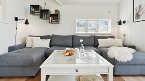 A modern living room with a grey sectional sofa, a white coffee table, and a window with blinds.