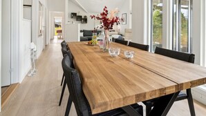 A spacious dining area with a wooden table, black chairs, and a woven pendant light.