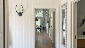 A hallway with a wooden floor, a white door frame, and a mirror with an ornate frame.