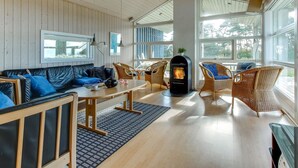 A cozy room with a wooden ceiling, a fireplace, wicker furniture, and large windows. - "Kajsa" - 50m from the sea by Interhome (Aakirkeby)