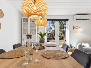 A dining area with a wooden table, woven placemats, and clear glassware.