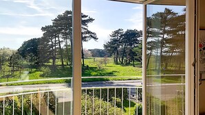 Ein Balkon mit Blick auf eine grüne Landschaft und Bäume.